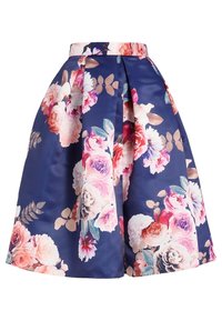 Mörkblå A-linjeformad kjol med stora rosa, vita och lila blommönster samt veck framtill och på sidorna.