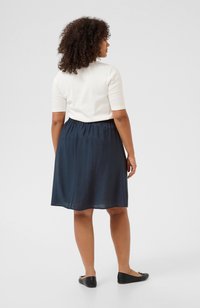 Navy blue skirt with an elastic waistband, made from lightweight fabric, paired with a fitted white short-sleeve top and black flats.