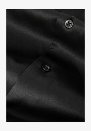 Tela negra con una textura suave, que presenta un botón negro y un brillo sutil. El material parece elegante y finamente tejido.