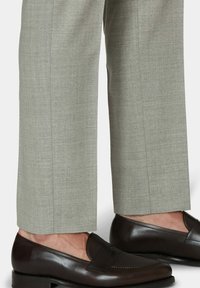 Hellgraue, maßgeschneiderte Hosen kombiniert mit dunkelbraunen Lederloafers mit glatter Oberfläche und dezenten Stickdetails.