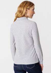 Grijze lange mouwen polo shirt met een kraag, gladde textuur en zijsplitten, gecombineerd met donkere jeans. Achteraanzicht van het kledingstuk is getoond.