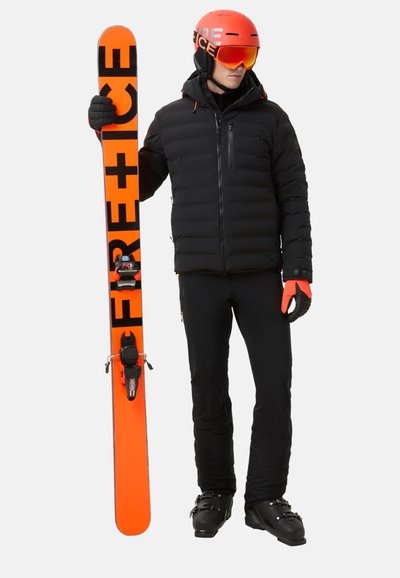 Skioutfit met een zwarte geïsoleerde jas, oranje handschoenen en zwarte skibroek. Houdt een oranje en zwarte ski met bindingen vast. Oranje helm en skibril.
