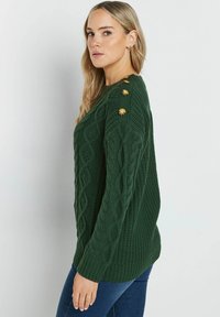 Zielony sweter dżersejowy z długimi rękawami, teksturowany wzór i ozdobne złote guziki na lewym ramieniu. Miękki, przytulny materiał.