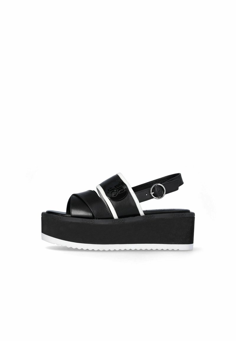 Sandale plateforme noire avec bordure blanche, bout ouvert, bride à la cheville avec boucle et semelle épaisse avec semelle extérieure blanche rainurée.