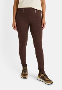 Leggings ajustados marrones con una textura suave, que cuentan con dos botones decorativos en la cintura y costuras en contraste a lo largo de los lados.