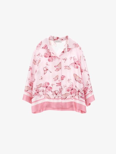 Jasnoróżowa bluzka z nadrukiem motyli w różnych odcieniach różu, z kołnierzykiem i dołem wykończonym jednolitą różową taśmą.