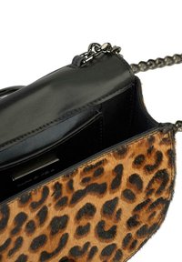 Borsa a tracolla con stampa leopardata, caratterizzata da dettagli in pelle nera, una tracolla a catena e un interno aperto con uno spazio per le carte. Texture morbida.