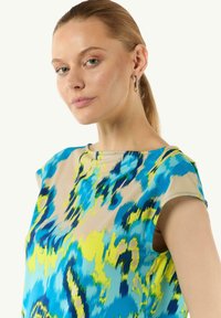 Korte mouw top met een multikleurig abstract patroon in blauw, groen en beige. Soepele stof met een ontspannen pasvorm en een ronde halslijn.