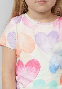 Korte mouwen shirt van katoen met een lichte achtergrond waarop meerkleurige aquarel harten in tinten roze, paars en oranje zijn afgebeeld.