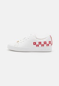 Baskets en cuir blanc avec une semelle plate, un bout rond, un système de laçage et un logo KORS rouge sur le côté. Le logo latéral comprend "MICHAEL KORS."