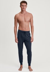 Navyblauwe loungebroeken van zachte stof, met een elastische tailleband met koord, en boordjes bij de enkels, en twee zijzakken.