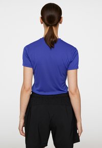 Kungsblå kortärmad skjorta med rund halsringning, kombinerad med svarta shorts med elastisk midja, utan märkbara mönster eller accenter.