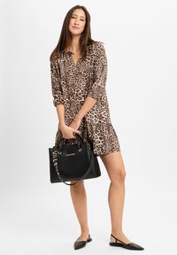 Leopardenmuster-Kleid mit langen Ärmeln, V-Ausschnitt und einem gerafften Saum, kombiniert mit einer schwarzen Lederhandtasche mit goldenen Akzenten und Griffen.