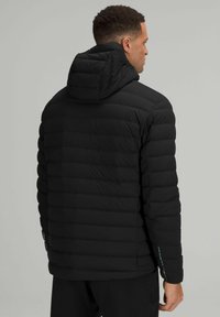 Schwarze Pufferjacke mit horizontalen Nähten, Kapuze und reflektierenden Details an den Ärmeln. Glatte Textur und leichtes Design für Wärme.