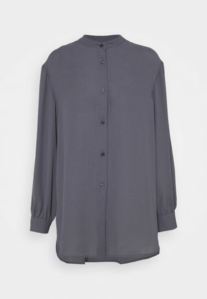 Blouse boutonnée à manches longues gris foncé avec un col mandarin et des poignets froncés, présentée sur un fond blanc uni.