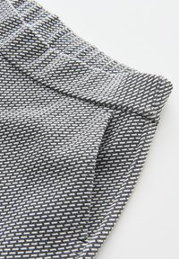 Woven fabric with a black and white geometric pattern, featuring a textured surface and a folded waistband.