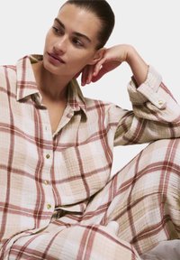 Set di pigiama a quadri, beige e marrone, composto da una camicia con colletto, bottoni e taschino; tessuto morbido e testurizzato.