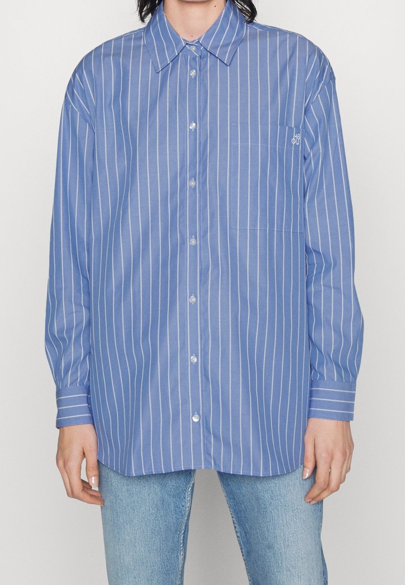 Blau gestreiftes Hemd mit Knopfleiste, Kragen, einer Brusttasche und langen Ärmeln. Leichter Stoff mit weißen vertikalen Streifen.