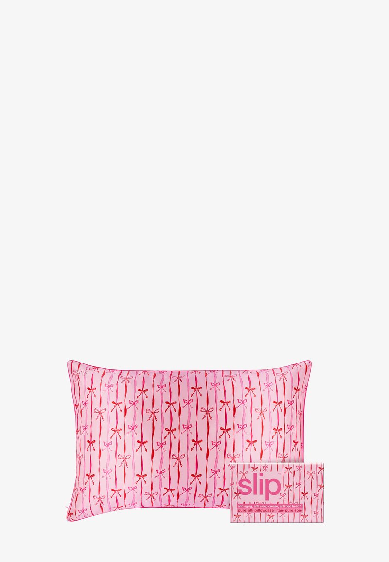 Roze zijden kussensloop met een patroon van rode strikken op verticale lijnen, vergezeld van een kleine bijpassende productdoos met het label "slip."