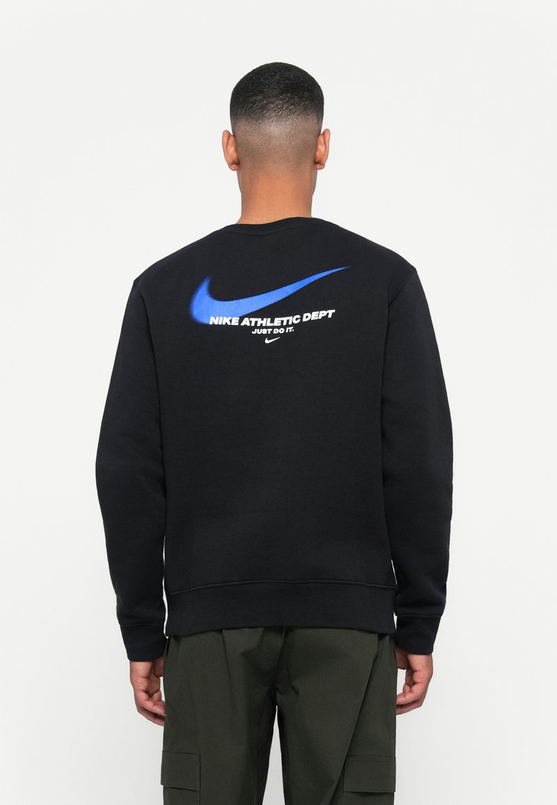 Black sweatshirt with crew neck, featuring a large blue Nike swoosh and text on the back. Made of cotton blend fabric, with ribbed cuffs.