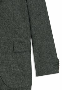 Gray textured blazer sleeve with a single pocket and four button accents on the cuff, featuring a subtle weave pattern.