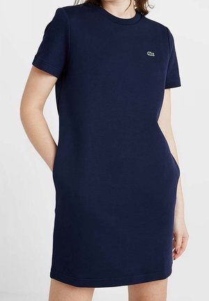 Dunkelblaues Jerseykleid mit kurzen Ärmeln und Rundhalsausschnitt. Verfügt über ein strukturiertes Schulterpanel und ein kleines grünes Krokodillogo. Keine sichtbaren Verschlüsse.