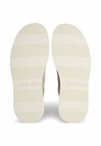 Calvin Klein calzature con tomaia beige chiaro, suole in gomma bianche, strisce testurizzate e logo in rilievo sul tallone.