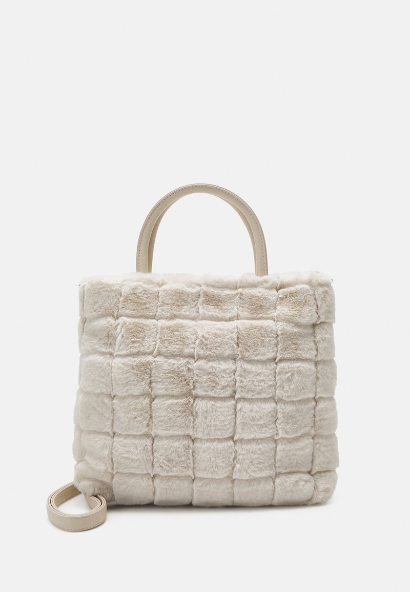 Sac à main en fausse fourrure beige avec motif matelassé carré, poignées supérieures et bandoulière amovible sur fond blanc.