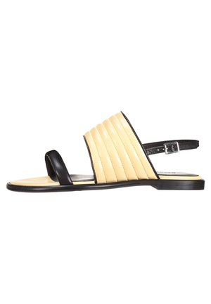 Flad sandal med beige polstret bred rem, sort tåloop, sort anklerem med sølvspænde og sort sål.