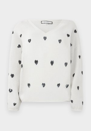 Pull blanc à col en V, avec une texture douce et des cœurs en sequins noirs disséminés. Manches longues et coupe décontractée.