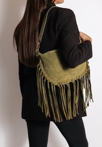 Borsa a spalla in suede verde oliva con dettagli in frange, forma arrotondata e una singola tracolla. Presenta una texture morbida e dettagli cuciti.
