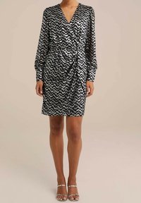 Black and white zigzag patterned dress with a wrap design, long sleeves, and a gathered waist detail. Smooth fabric with a slight sheen.
