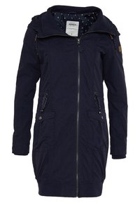 Granatowa kurtka z zapięciem na zamek, dwoma przednimi kieszeniami, regulowanymi trokami oraz podszewką w kapturze. Posiada wewnętrzny wzór w kropki.