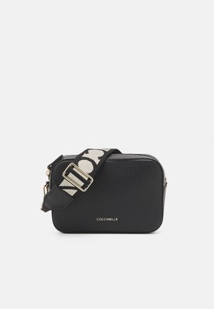 Black textured leather rectangular crossbody bag with gold zipper and adjustable strap featuring bold black and white pattern.