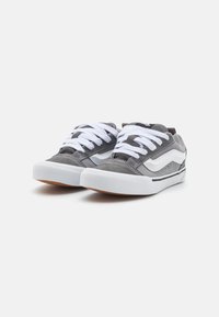 Baskets de skate en daim gris avec des lacets blancs et une semelle en caoutchouc ivoire. Dotées d'un détail de rayure sur le côté et d'un motif texturé sur le dessus.