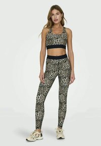 Leopard print sports bra and leggings set, featuring a black waistband. Made from stretchy fabric, designed for comfort and movement.