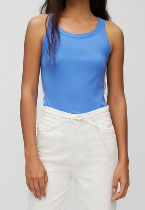 Niebieski, dopasowany top na ramiączkach z mieszanki bawełny z okrągłym dekoltem. Połączony z białymi dżinsami z paskiem i przednimi kieszeniami.
