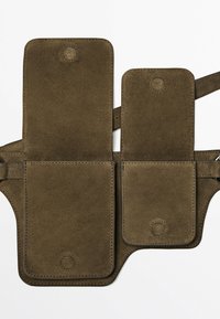 Pochette double en daim marron avec fermetures à rabat et bandoulière réglable, conçue pour transporter de petits objets en gardant les mains libres.
