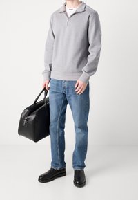 Gray zip-up sweatshirt, blue jeans, black leather bag, and black boots. The sweatshirt has ribbed cuffs and a textured fabric.