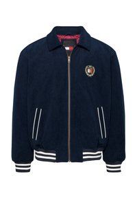 Giacca bomber navy in materiale morbido, con un emblema dorato, polsini a strisce bianche e tasche laterali con zip e bordo bianco.