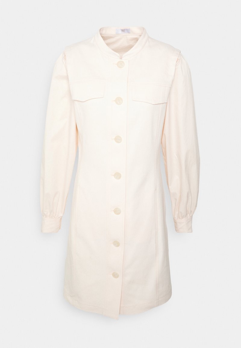 Robe crème à manches longues boutonnée, col montant, deux poches poitrine à rabat et poignets froncés.