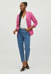 Fuksia blazer med skreddersydd passform og tre kvart ermer, kombinert med lyseblå høytlivsjeans og svarte stroppesandaler.