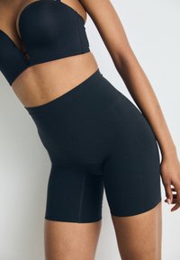 Black high-waisted shorts with a smooth texture and a snug fit, extending to mid-thigh, designed for comfort and support.