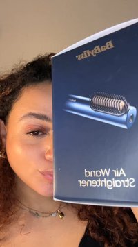 Babyliss Air Wand rettetang i elegant blå design, med et kamlignende varmeelement og glanset finish. Forsiden av esken er synlig og viser produktnavnet.