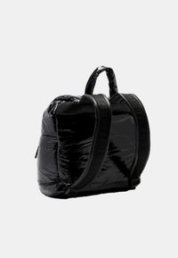 Zaino nero realizzato in materiale imbottito lucido, con doppie spalline, una maniglia superiore e una tasca laterale con zip. Texture liscia, forma strutturata.