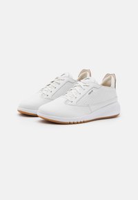 Zapatillas blancas con paneles perforados, punta redondeada, diseño con cordones y una lengüeta trasera de sintético marrón. Suela de goma con tracción.