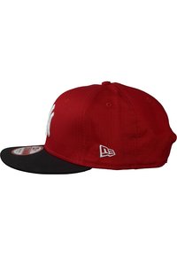 Gorra de béisbol roja con visera negra, que presenta un logotipo bordado en blanco en la parte frontal y un pequeño parche con logo en el lateral. Tela de algodón.