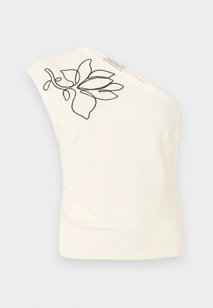 Haut asymétrique ivoire avec un motif floral abstrait brodé noir près de l'encolure et une petite étiquette de marque en tissu.