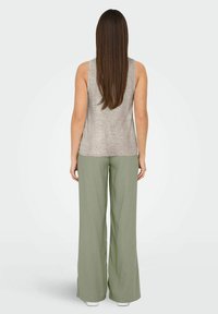Top gris sin mangas acompañado de pantalones sueltos de un verde claro. La tela parece suave con una textura lisa y un corte relajado.