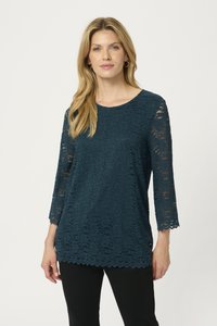 Top in pizzo teal con maniche a tre quarti, orlo scallop e un intricato motivo floreale abbinato a pantaloni neri. Tessuto leggero e traspirante.